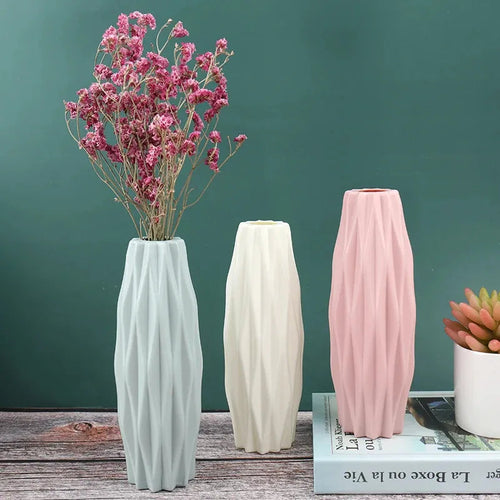 Modern ceramic vases with geometric ridges, holding dried pink flowers, styled on rustic wood for home decor