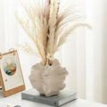 Modern ceramic vase with dried pampas grass and white flower, styled on book for cozy home decor