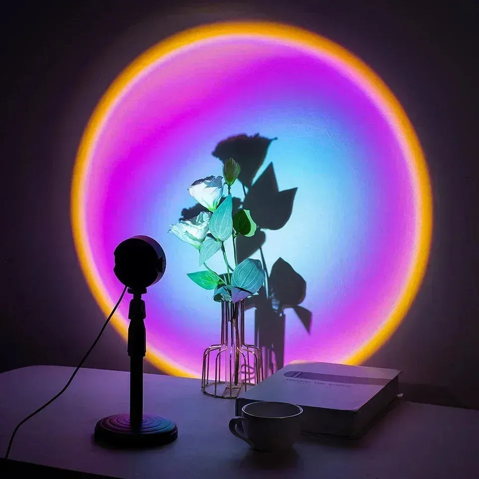 Colorful LED projector lamp casting rainbow circle glow on wall with flower vase, book, and mug on desk