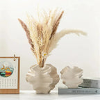 Leaf-shaped ceramic vase with dried pampas grass, styled on shelf with books and calendar for cozy home decor