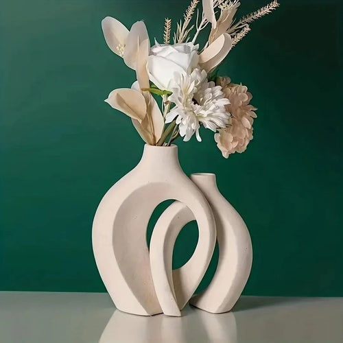 Modern ceramic vase with abstract cutouts holding white flowers, minimalist home decor against green wall