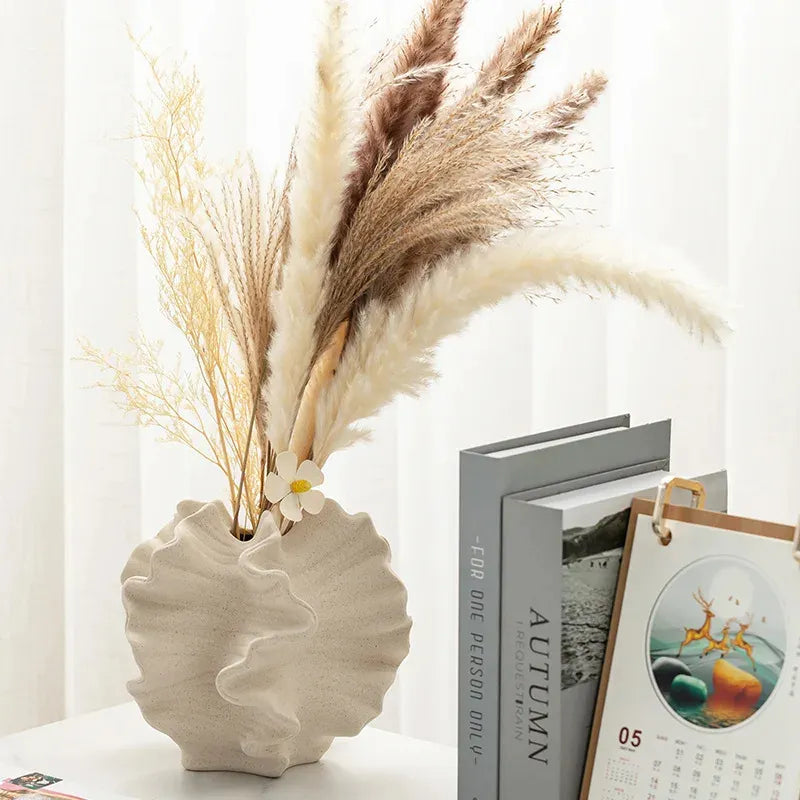 Cream ceramic vase with dried pampas grass and wildflowers, styled with books and calendar for cozy home decor