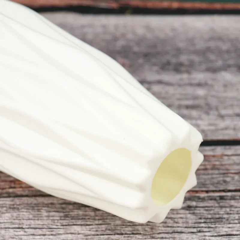 White ribbed ceramic vase with fluted design on rustic wood surface