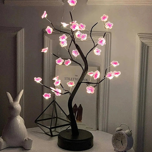 Glowing pink cherry blossom tree lamp with black branches, perfect for cozy bedroom or desk decor.