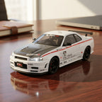 White Nissan Skyline GT-R diecast model with carbon hood, racing decals, and black rims on wooden desk