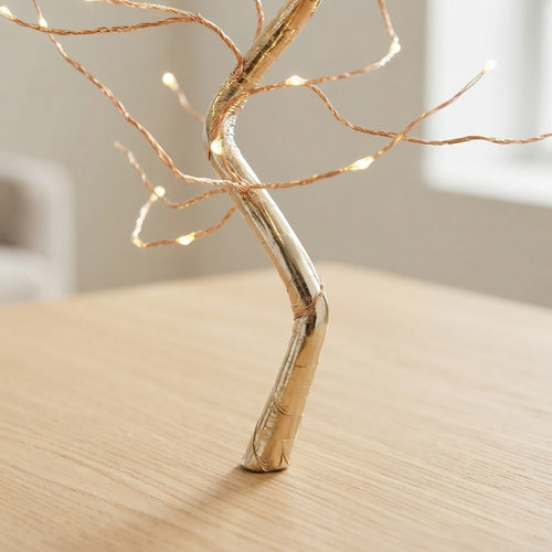 Gold wire tree with warm fairy lights on wooden table, cozy home decor accent